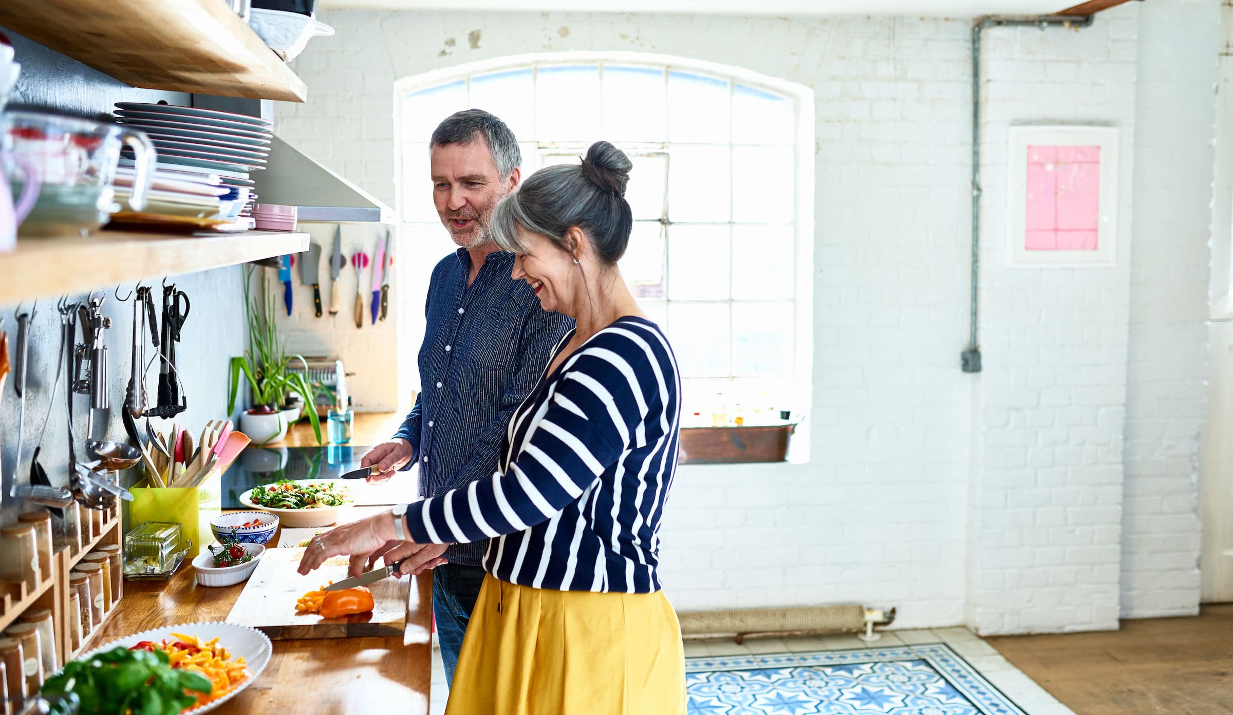 Mature couple preparing vegetarian meal in stylish kitchen