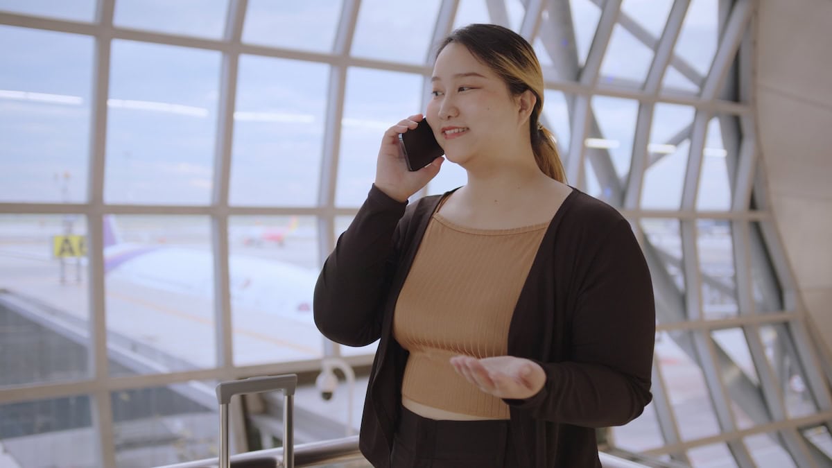A,Woman,Talking,On,Smartphone,At,Airport,Terminal,,With,Airplane